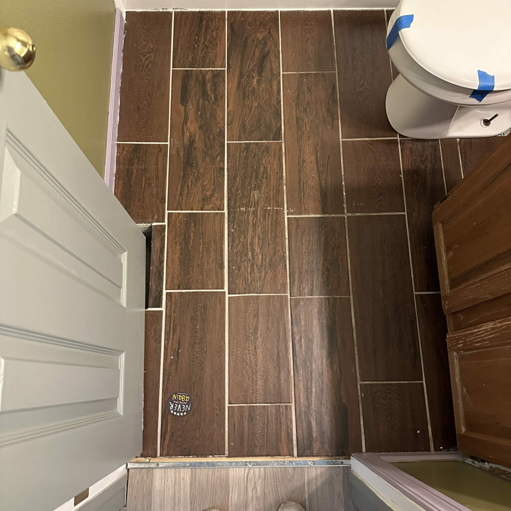 brown faux wood floor tile in a small bathroom