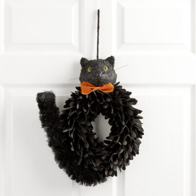 black cat wreath hanging on a white door with orange bowtie