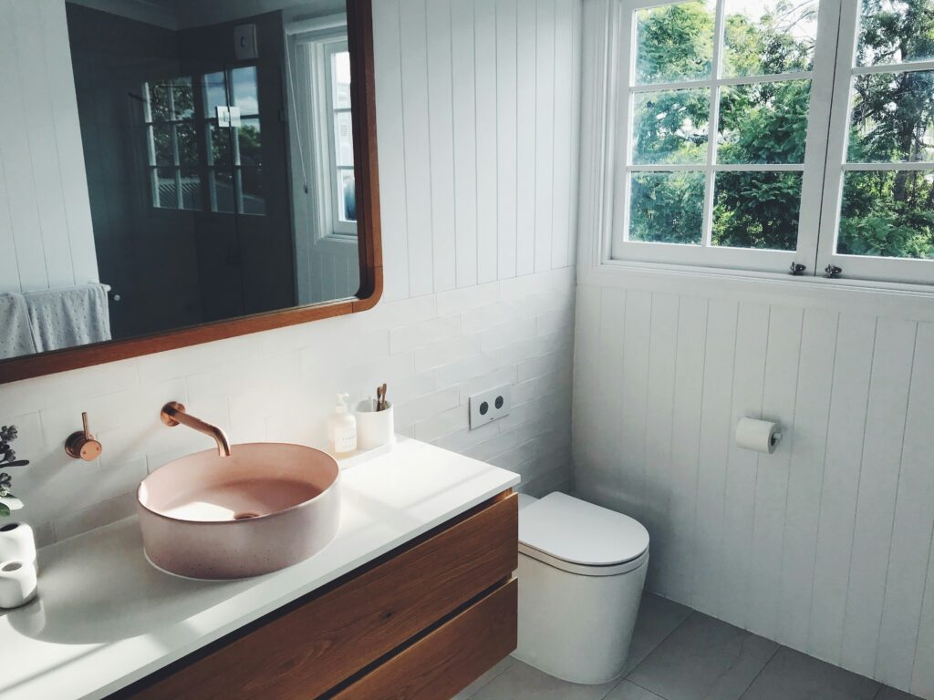 Pink sink sitting on a wood and white bathroom cabinet