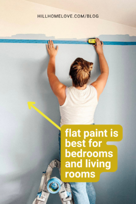 Woman measuring and painting a wall with flat paint, recommended for bedrooms and living rooms. The text explains flat paint is best for spaces where a smooth finish is desired.