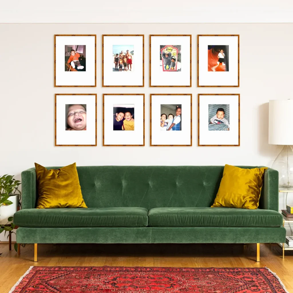 Green couch with set of 8 gold picture frames in a grid